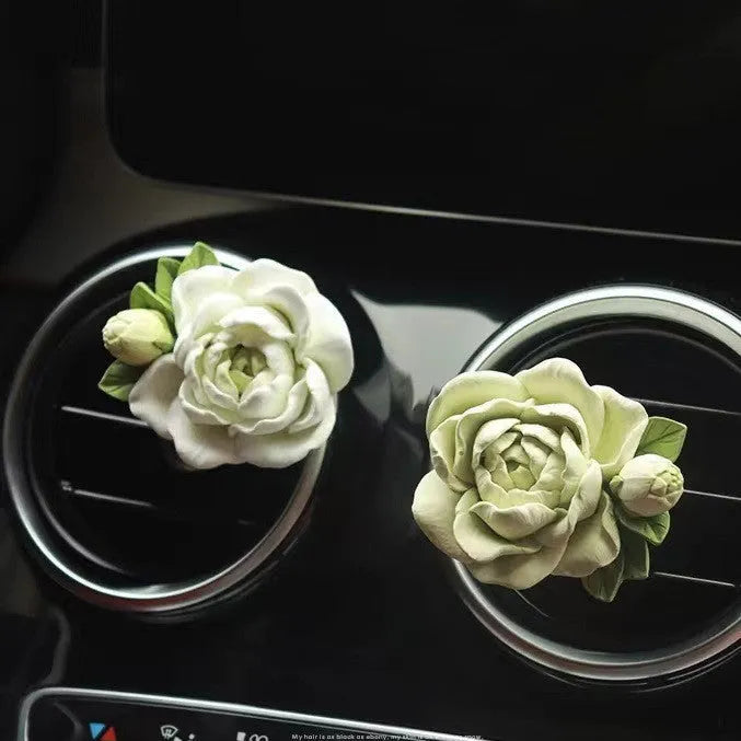 Solid jasmine car perfume diffuser clipped onto a car air vent, showing off white colour.