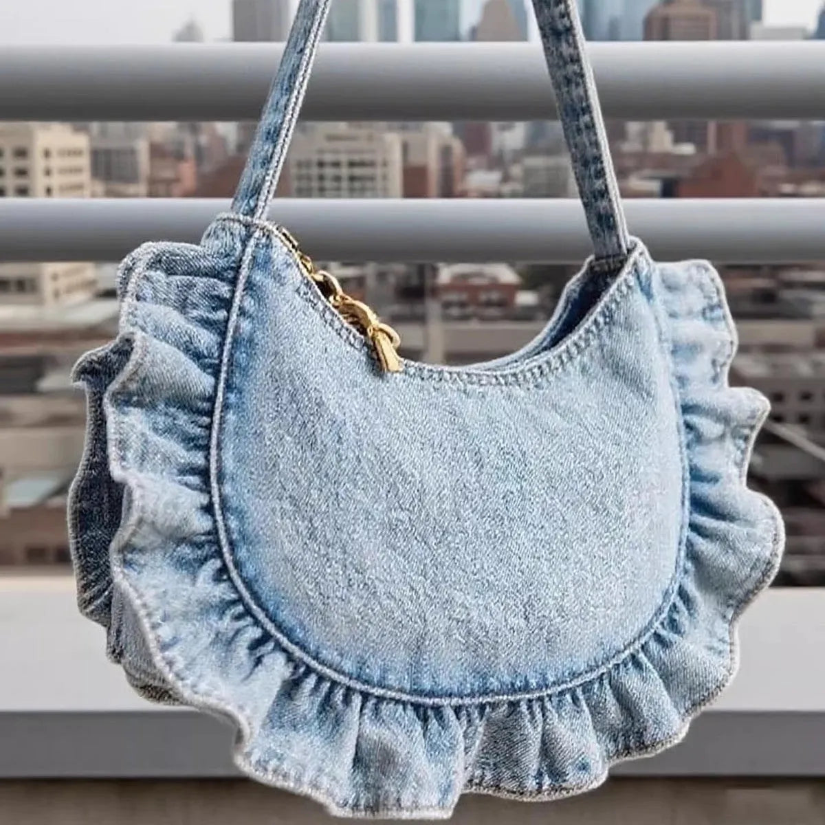Denim blue cross-body bag with lace pleated trim and single shoulder strap, bucket shape.