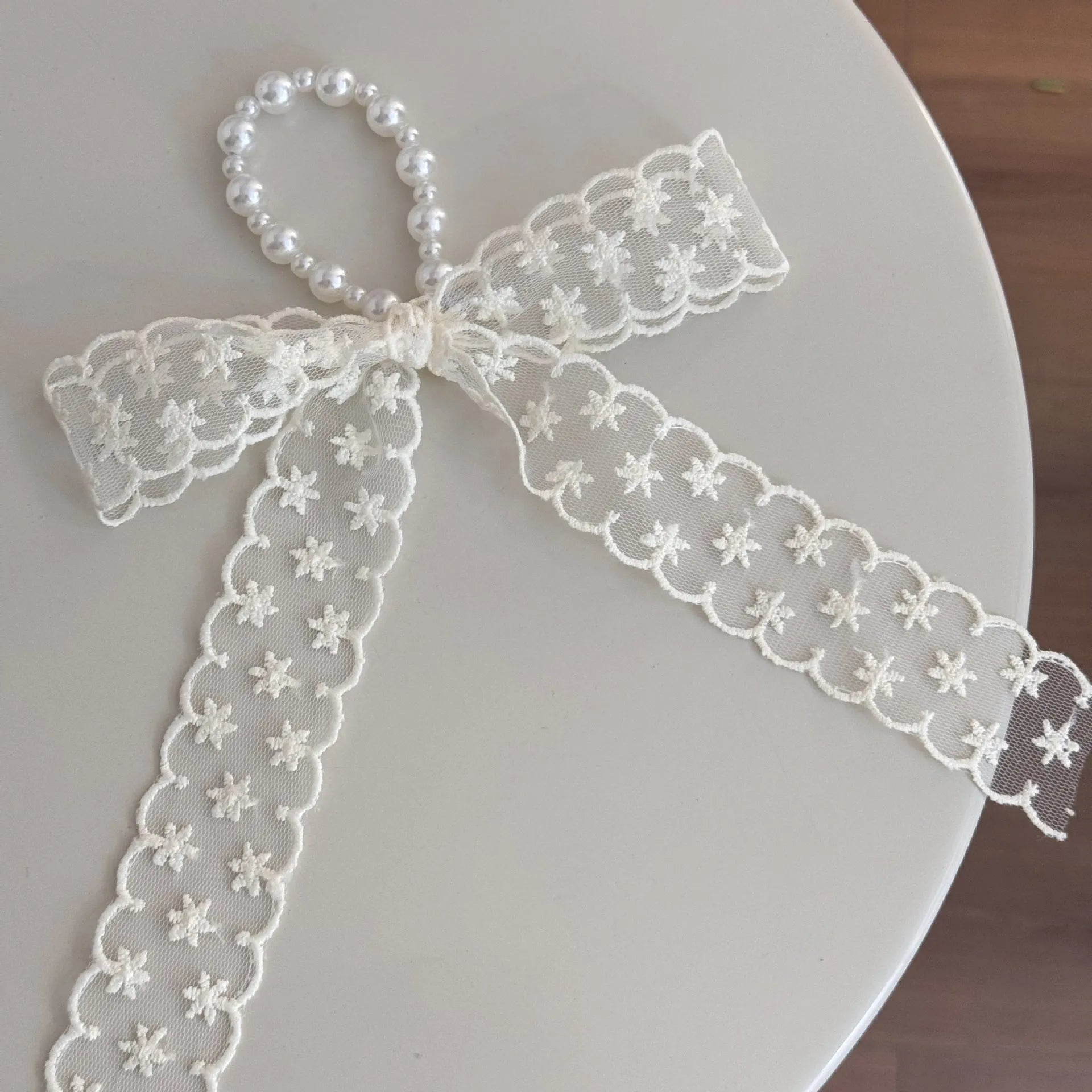 A women's hair clip barrette with a soft blue cloth bow and lace decoration on a plastic clip.