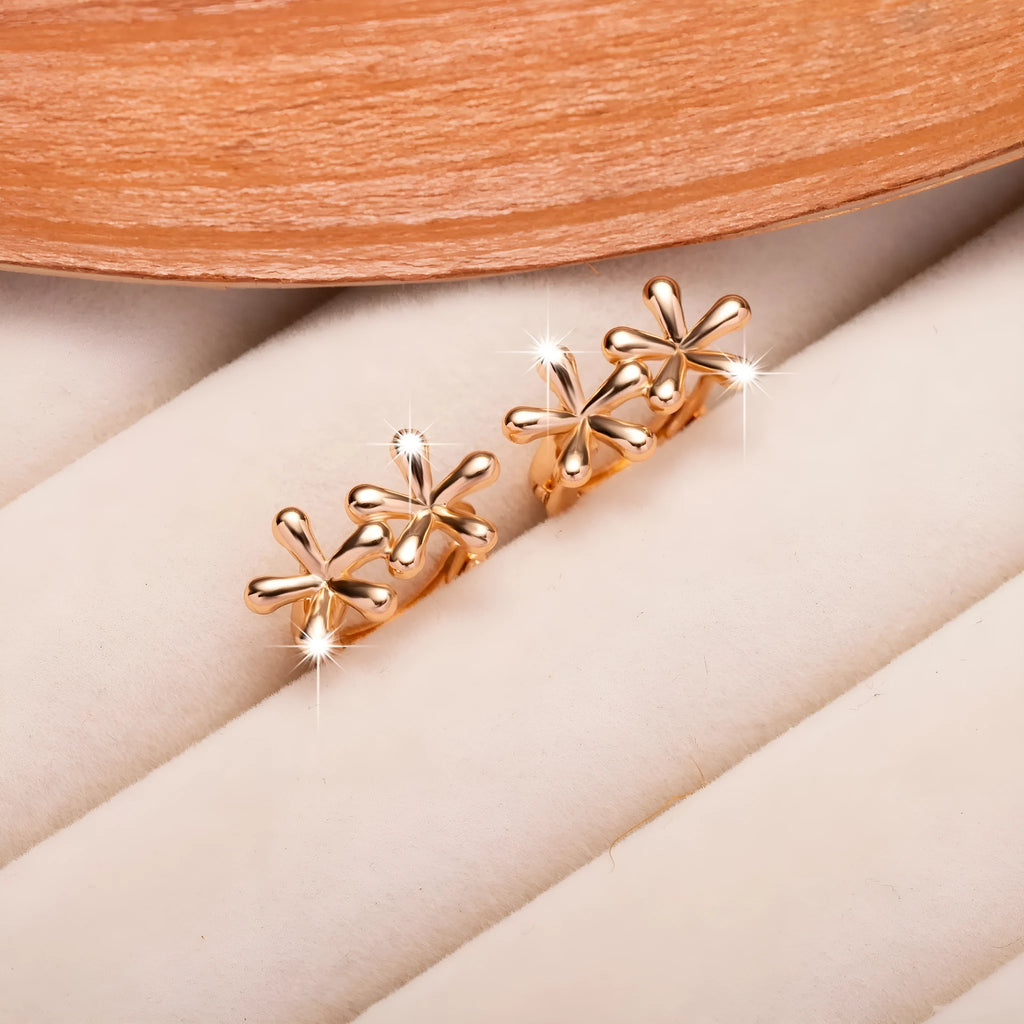 Close-up of rose gold drop earrings with 3D floral and waterdrop design on a white background.