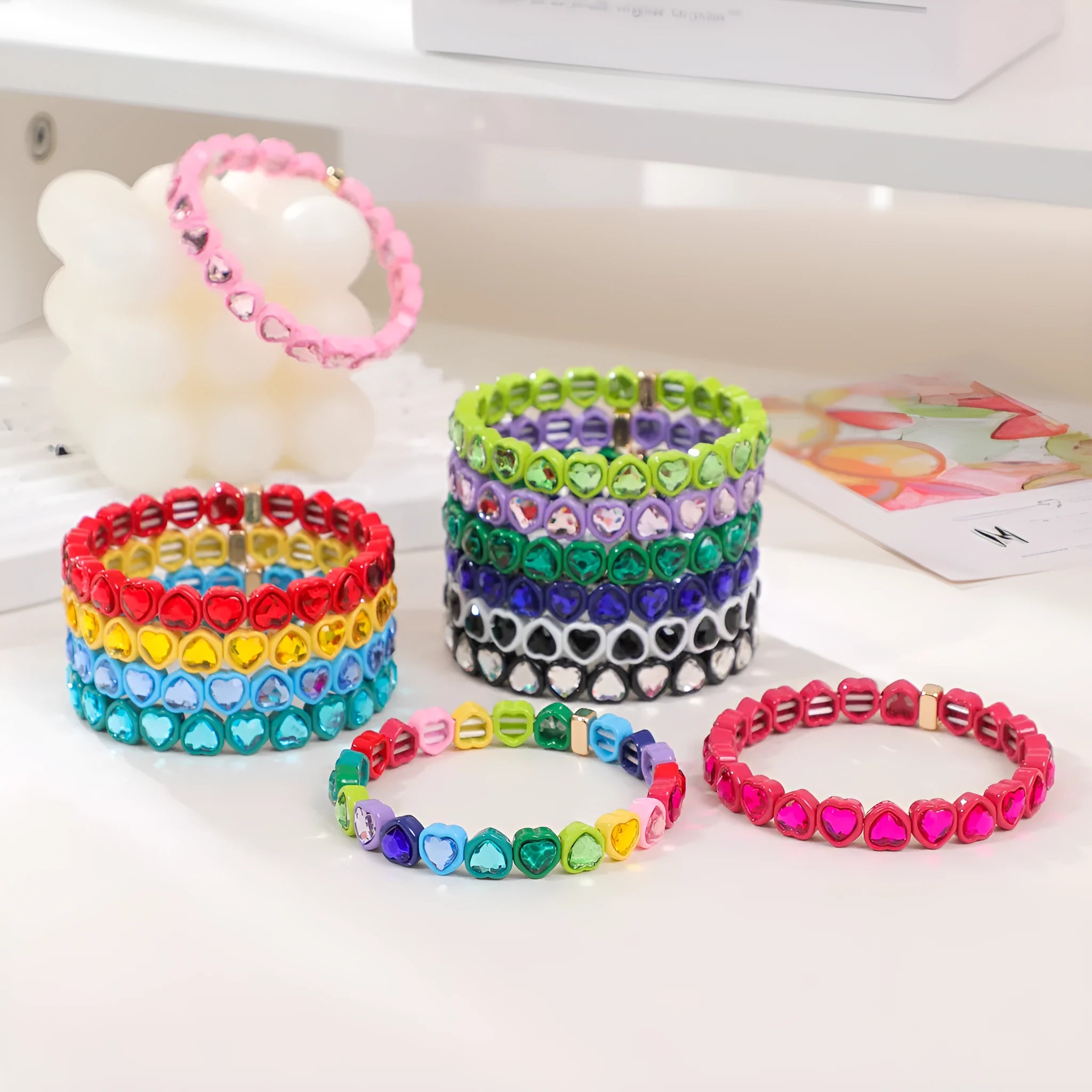 Colourful enamel heart-shaped stretch bracelet on a wrist showing the alloy and elastic band construction.