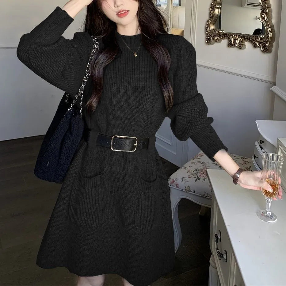 Long sleeve loose knitted dress for women in beige with a black belt, shown on a hanger.