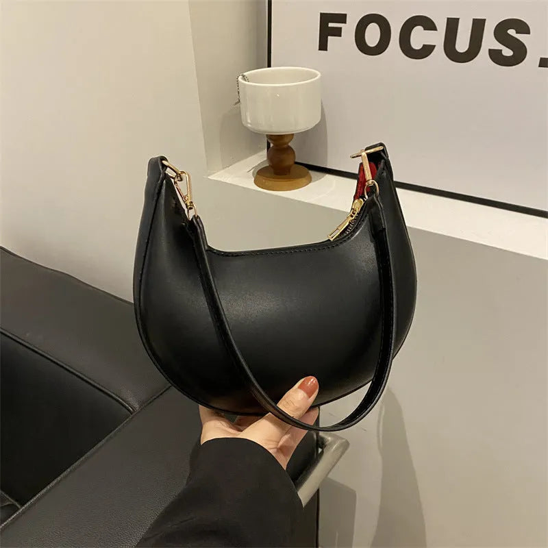 Round black women's one-shoulder underarm bag with sewing line details and a single strap.