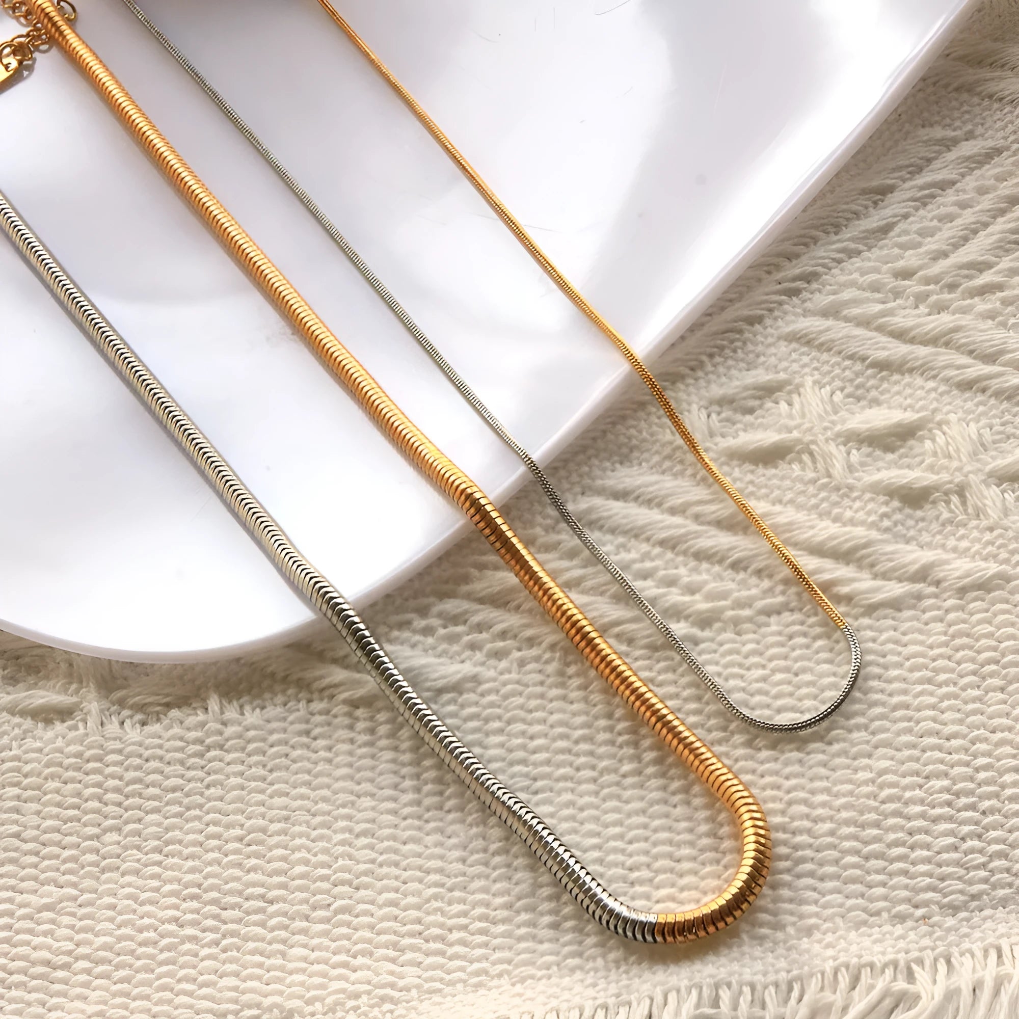 Gold-coloured snake bone chain necklace with geometric links on a white background.