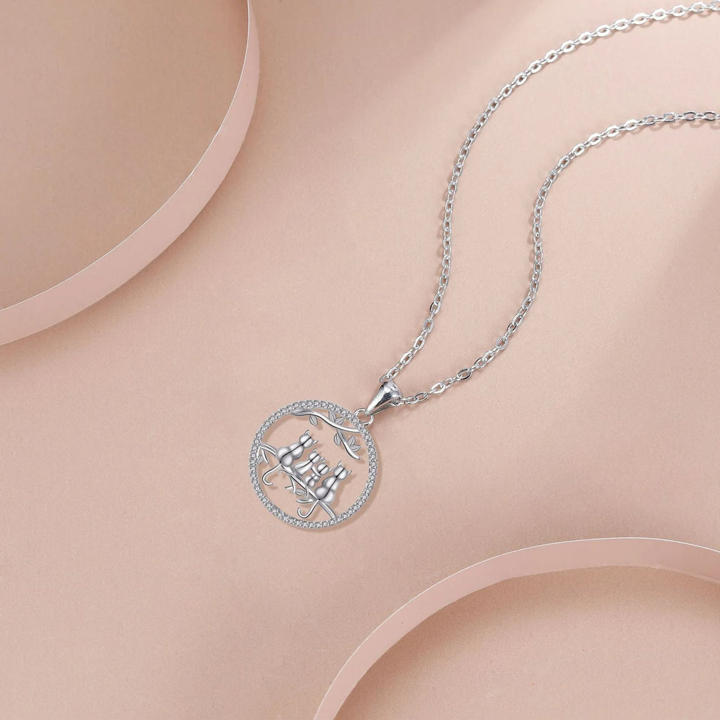 Close-up of a copper necklace with a pendant showing four kitten figures on a cross chain.