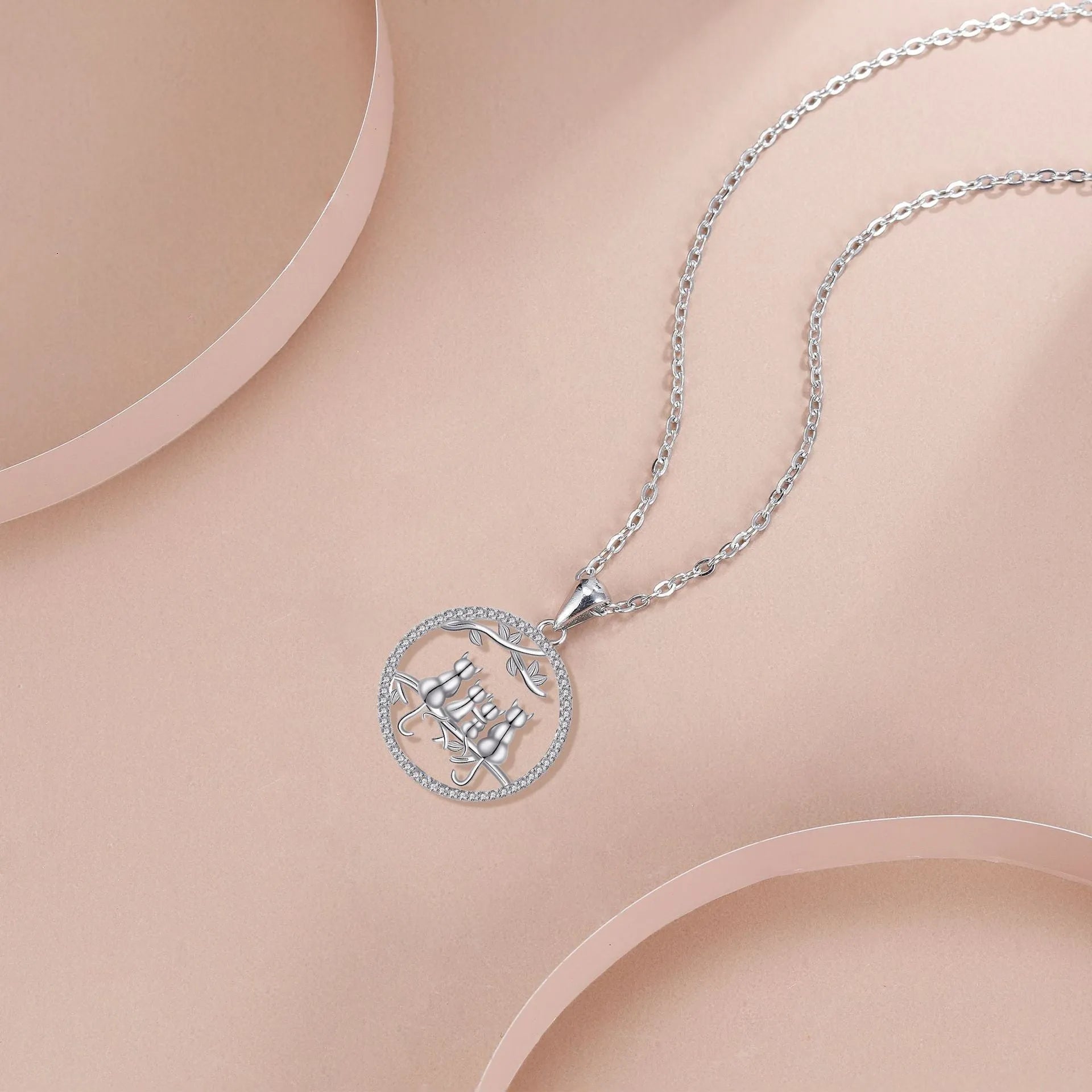 Close-up of a copper necklace with a pendant showing four kitten figures on a cross chain.