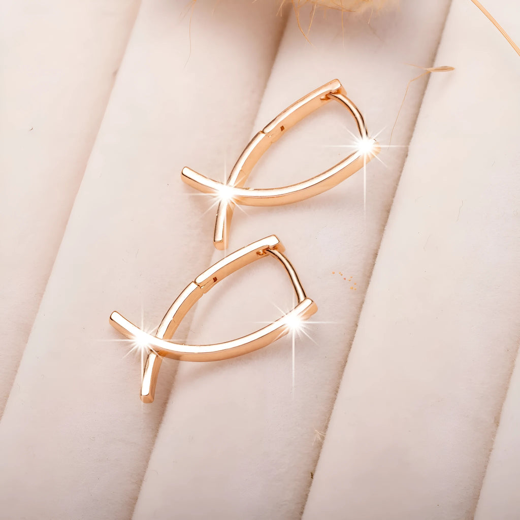 Rose gold cross shaped earrings on a plain background.