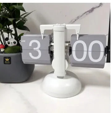 Small scale retro flip clock with black or white trim and black flip cards on a desk