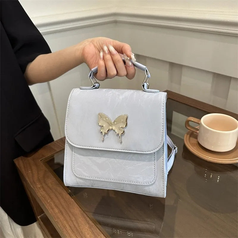 Preppy style white PU women's backpack with a black detachable bow decoration and visible stitching.