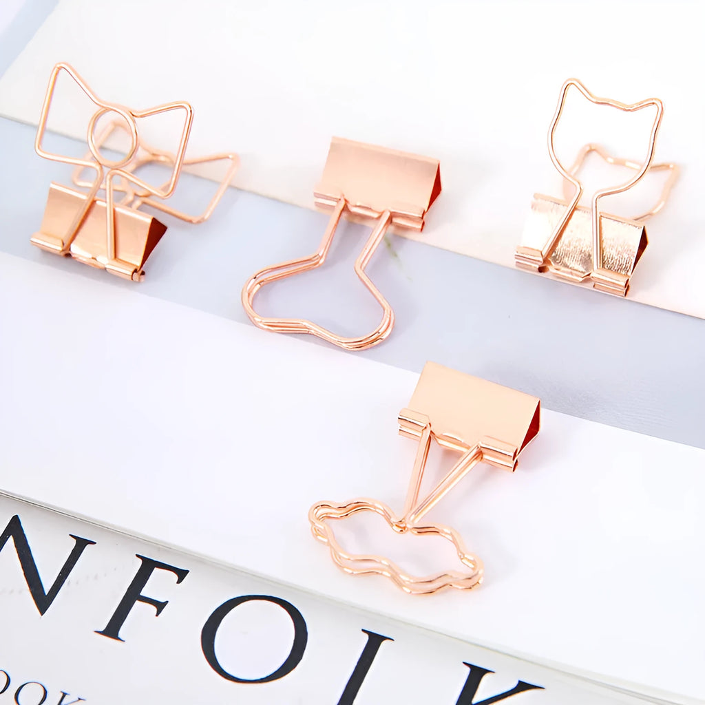 Small gold-plated metal office clip with a long tail, shown in decorative flamingo, love, cat, cactus, and bow shapes.