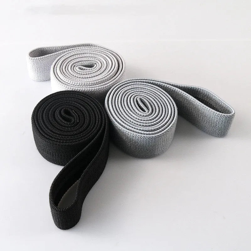 Three polyester cotton and latex silk resistance bands 200 x 4 cm in blue pink and purple on a flat surface