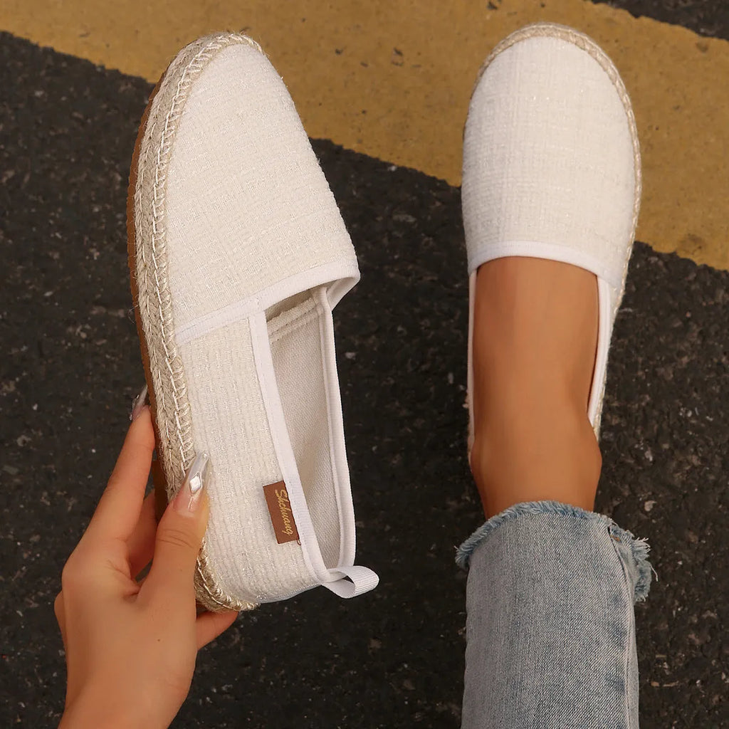 Casual beige canvas fisherman shoes with a rope sole and flat heel on a plain background.