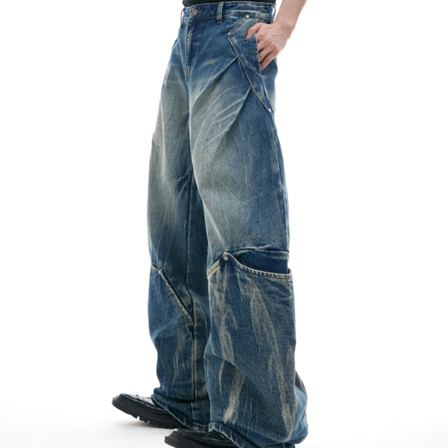 Man wearing verdant blue loose-fit jeans with a curved knife burst pattern on the thighs.