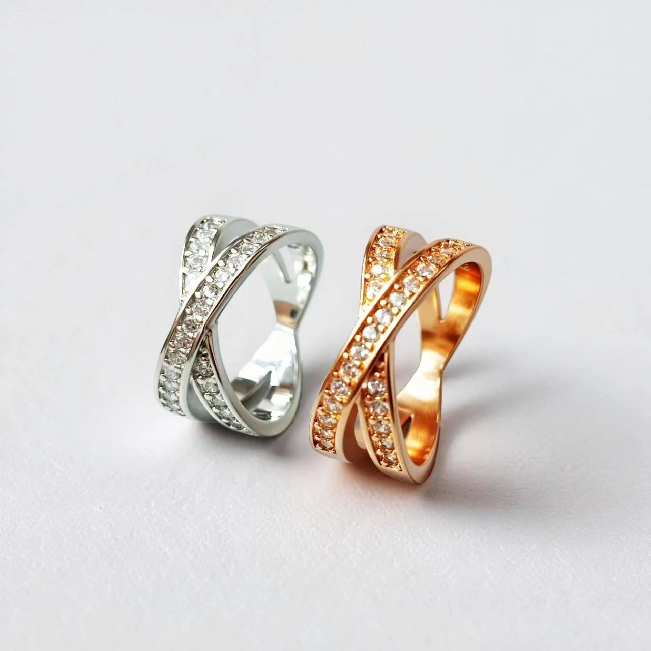 A silver or rose gold metal ring with a cross design and small micro-inlaid zircon stones.