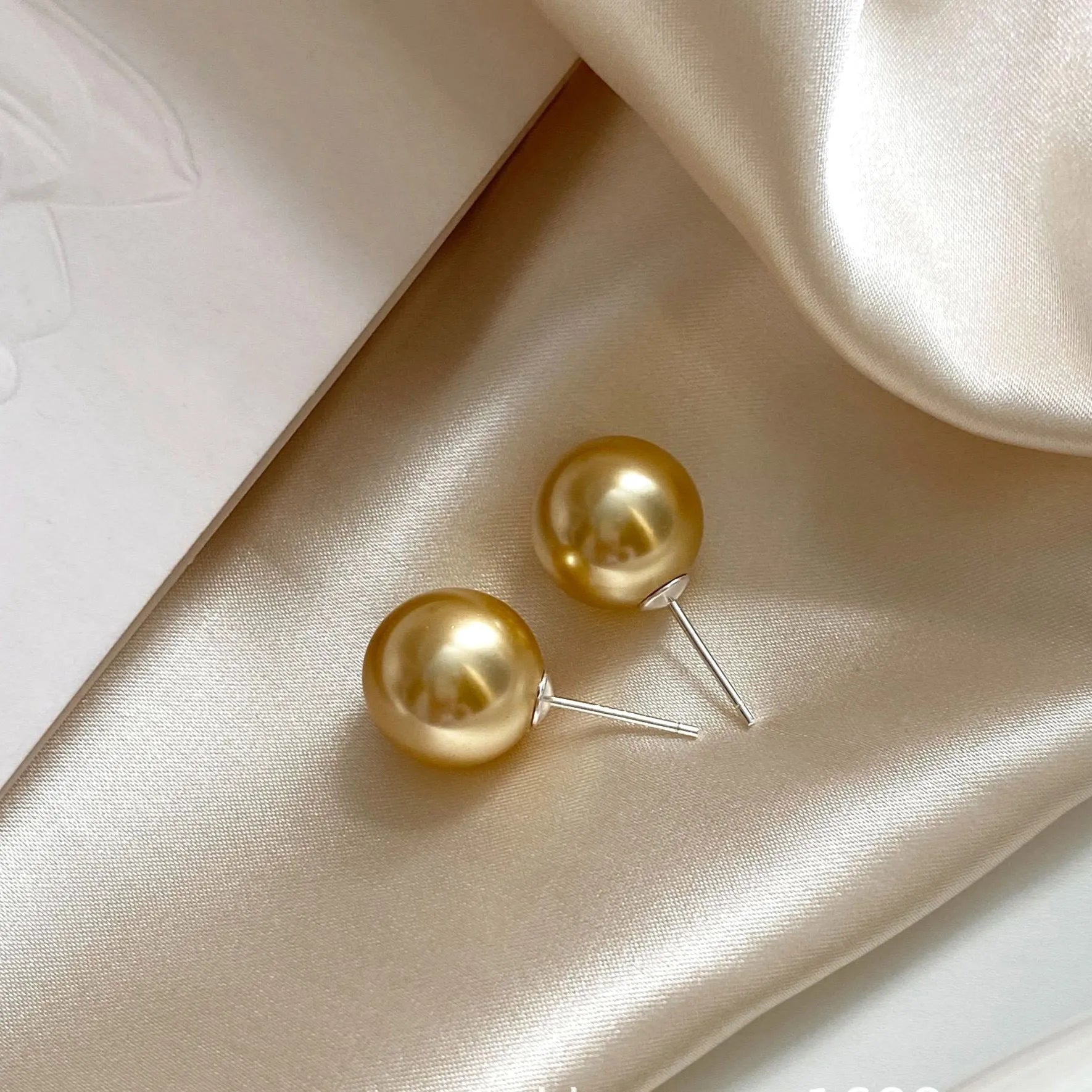 Geometric large pearl stud earrings with an eight-point star detail on a silver setting.