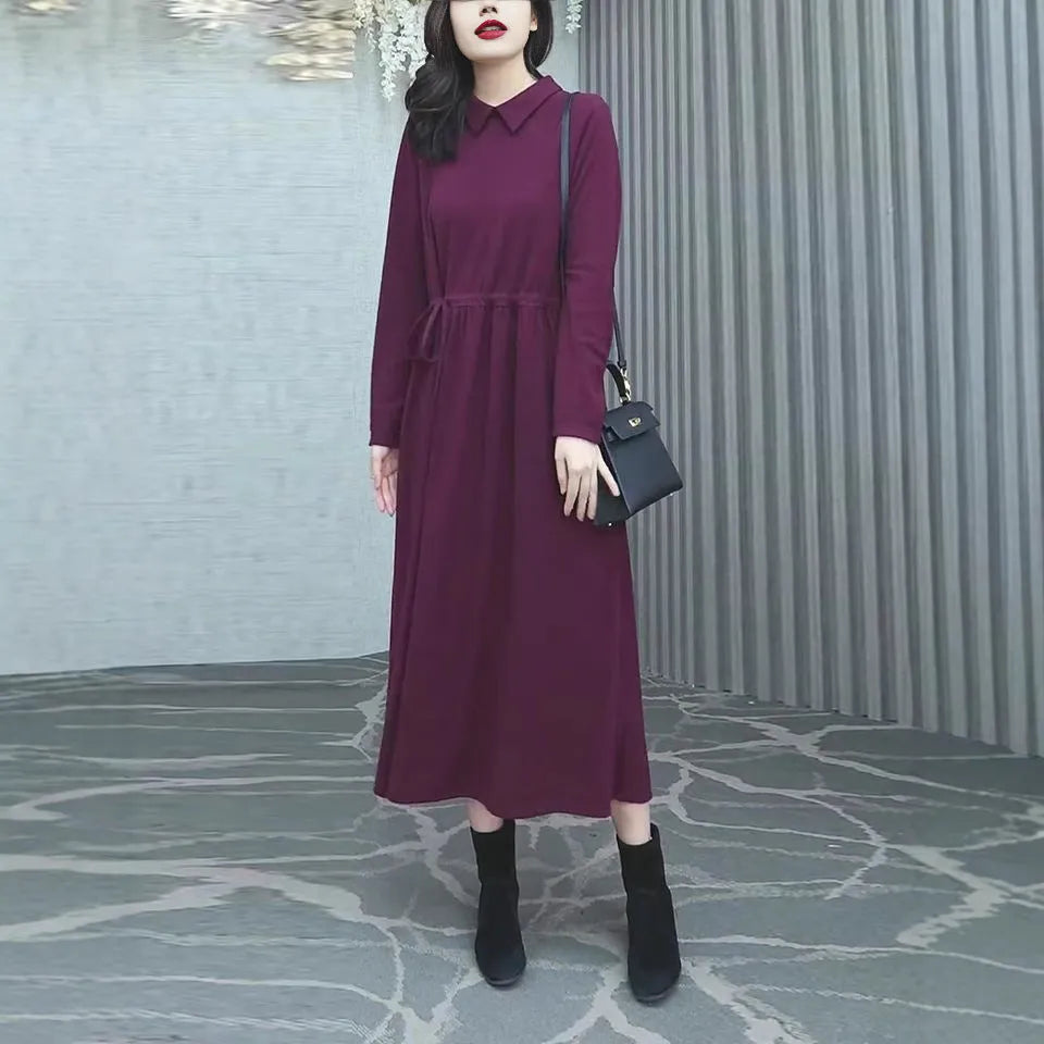 Purplish red women's long-sleeve maxi dress with extra-long cuffs and urban commute style on a hanger.