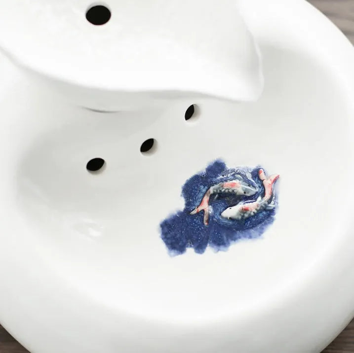 White ceramic automatic cat water dispenser with leaf design and US plug on a wooden floor