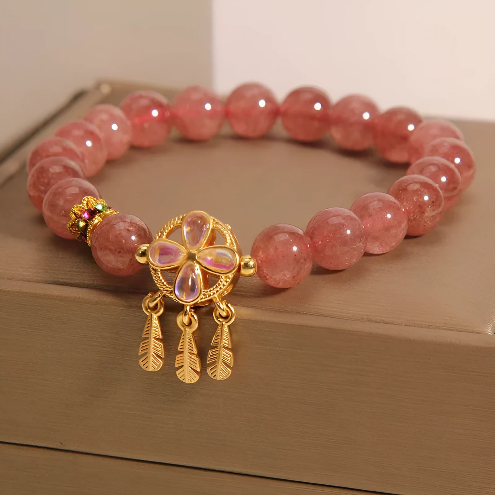 Women's strawberry quartz bracelet with a four-leaf clover dream catcher ball pendant.