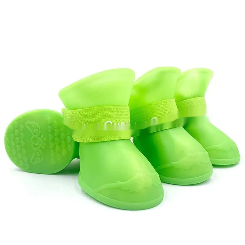 A set of four colourful rubber rain shoes for dogs, showing soft soles and bright pink, blue, orange, and red colours.