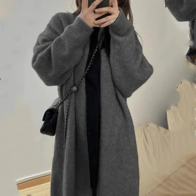 A woman wearing a loose, thick knitted chenille cardigan in a solid colour, showcasing its long sleeves and medium length.