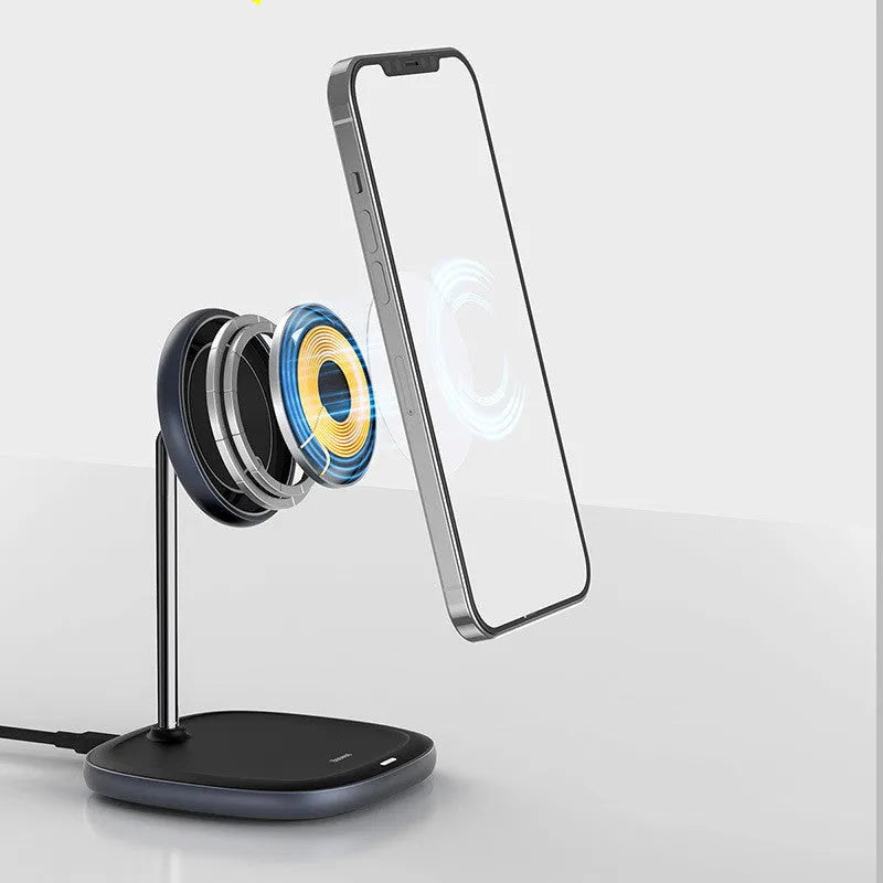 Black magnetic wireless charging stand holding an iPhone 12 upright on a desk.
