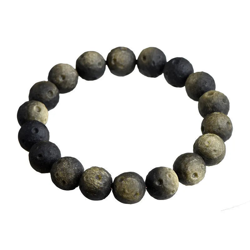 A natural obsidian crater ball bracelet in gold or silver meteorite colour on a wrist, showing textured bead detail.