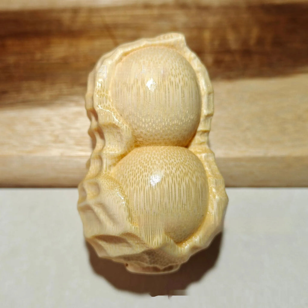 Solid natural bamboo peanut ornament with engraved message on wooden surface