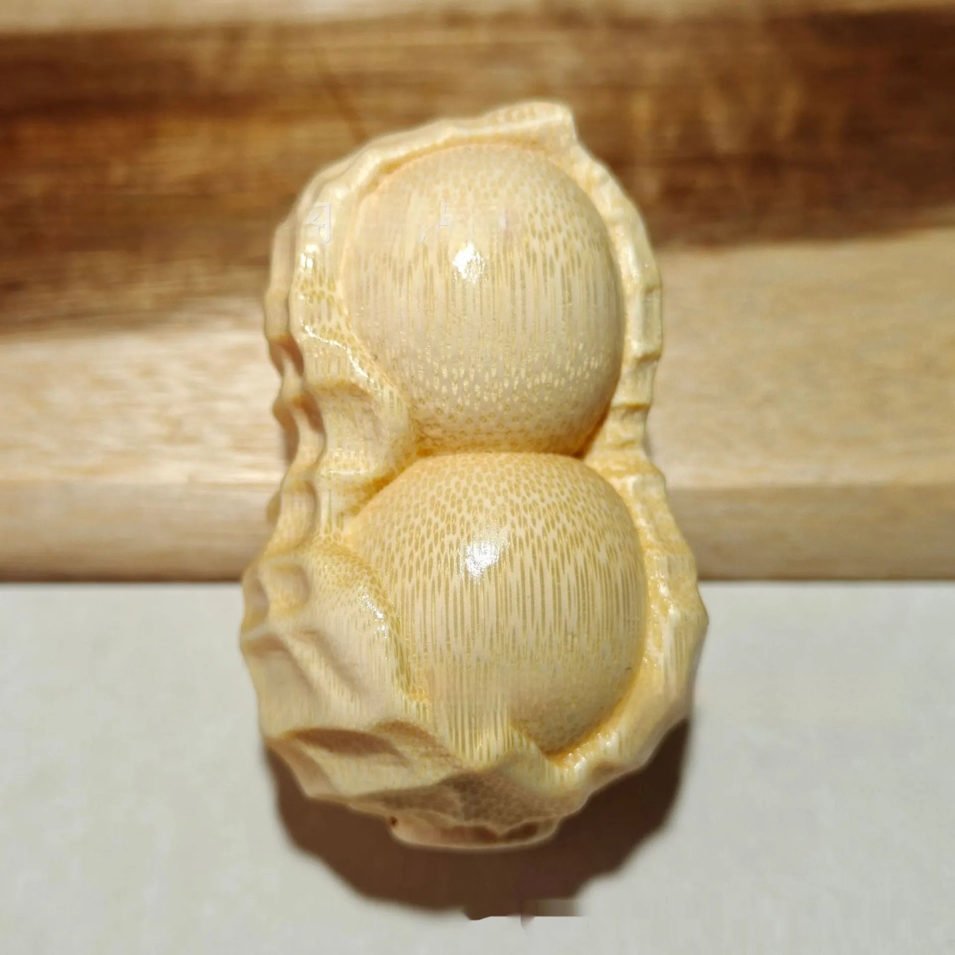 Solid natural bamboo peanut ornament with engraved message on wooden surface