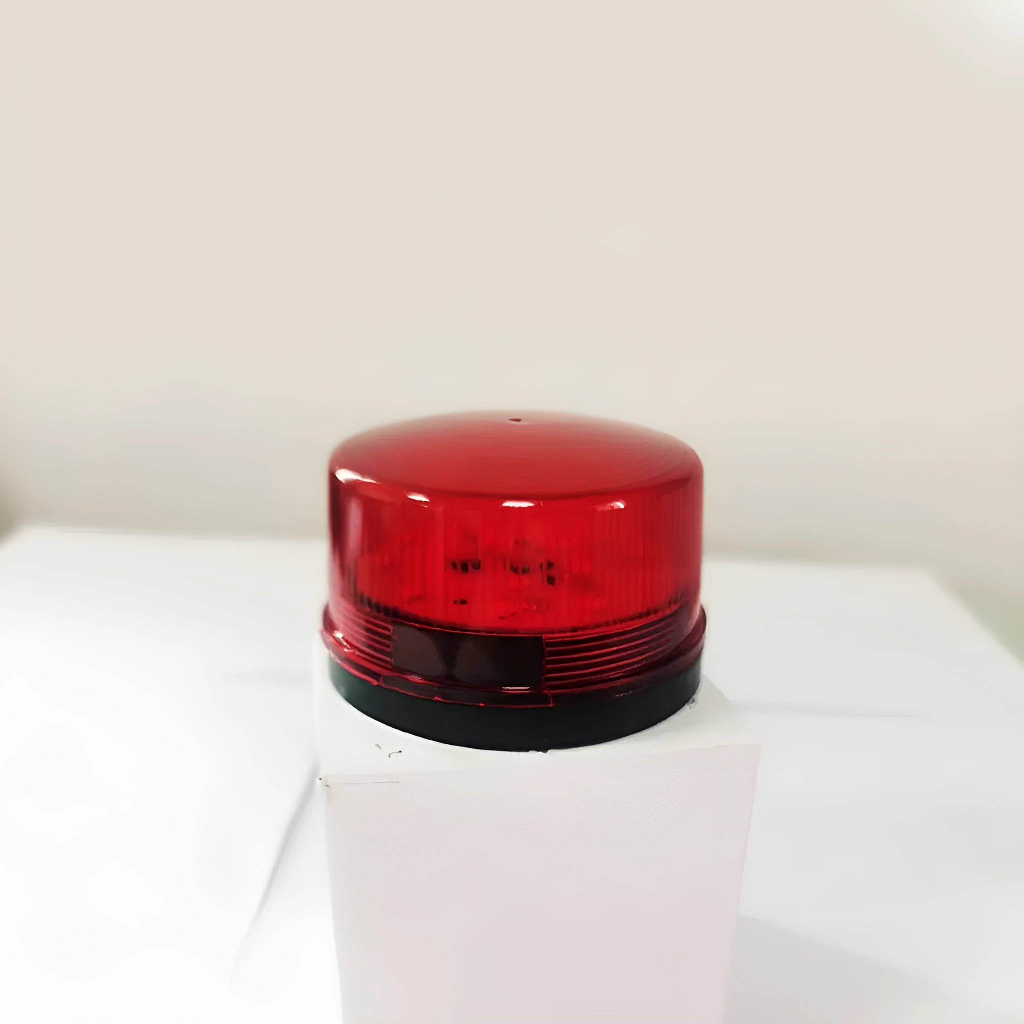 Small red 24V flashing warning light and alarm with mounting base.