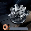 Silver solar-powered rotating fighter aircraft perfume ornament on a desk with essential oil bottle.