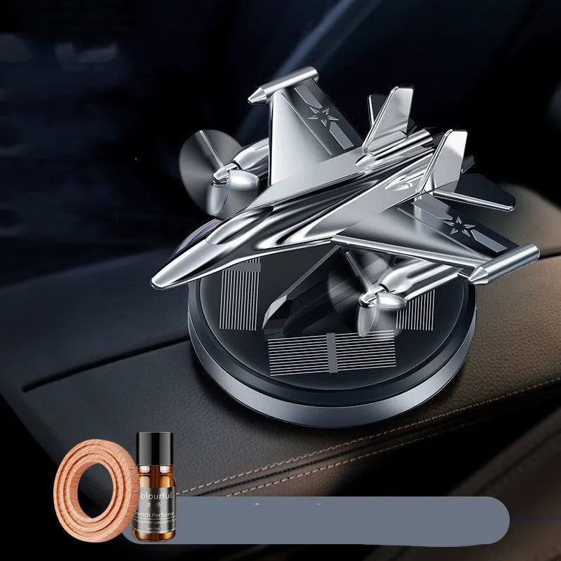 Silver solar-powered rotating fighter aircraft perfume ornament on a desk with essential oil bottle.