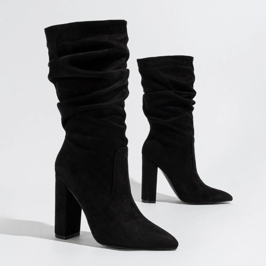 Women's black suede pointed-toe ankle boots with a chunky high heel, shown on a mid-calf.