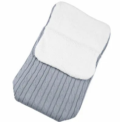 Envelope-style baby stroller sleeping bag in beige colour with thick filling, shown next to a pram.