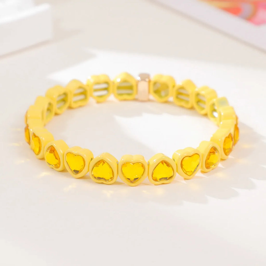 Colourful enamel heart-shaped stretch bracelet on a wrist showing the alloy and elastic band construction.