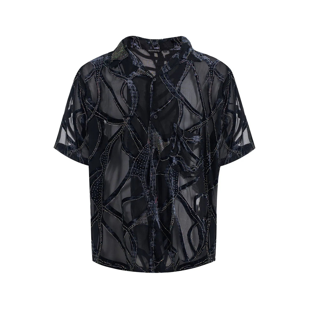 Man wearing a loose-fit black short-sleeved shirt with a translucent snake pattern print and lapel collar.