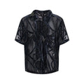 Man wearing a loose-fit black short-sleeved shirt with a translucent snake pattern print and lapel collar.