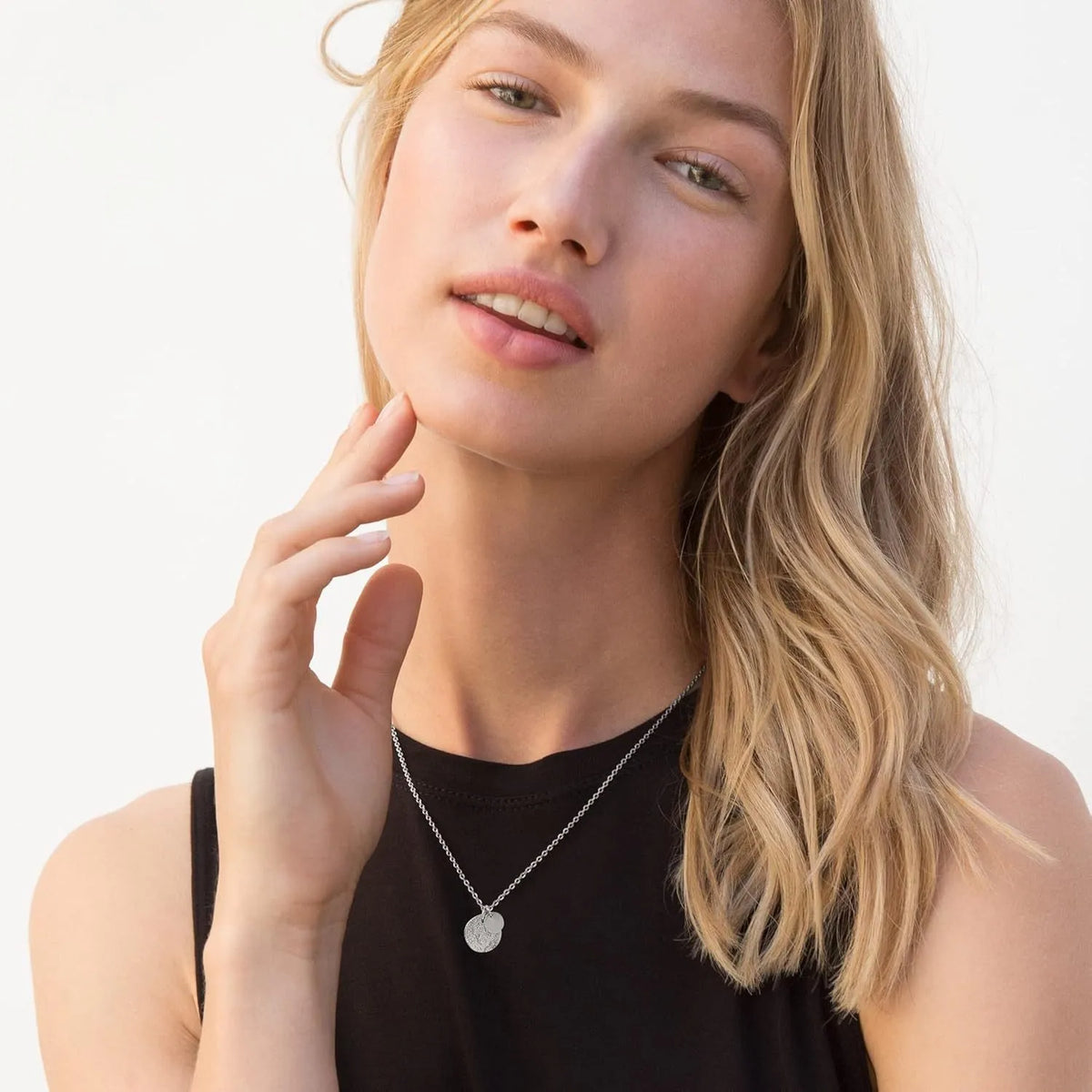 Round coin stainless steel pendant necklace in gold with adjustable side chain on a white background