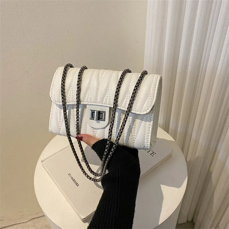Small beige retro diamond texture PU women's bag with a shoulder strap on a table.