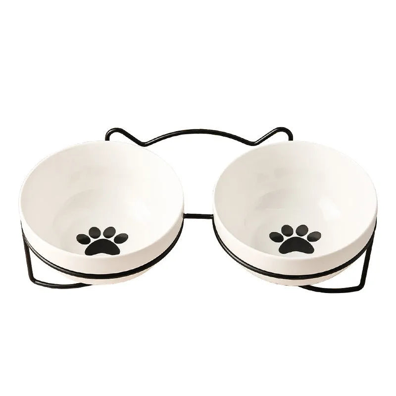 White ceramic cat bowl with cat footprint design on a black iron stand with cat ears.
