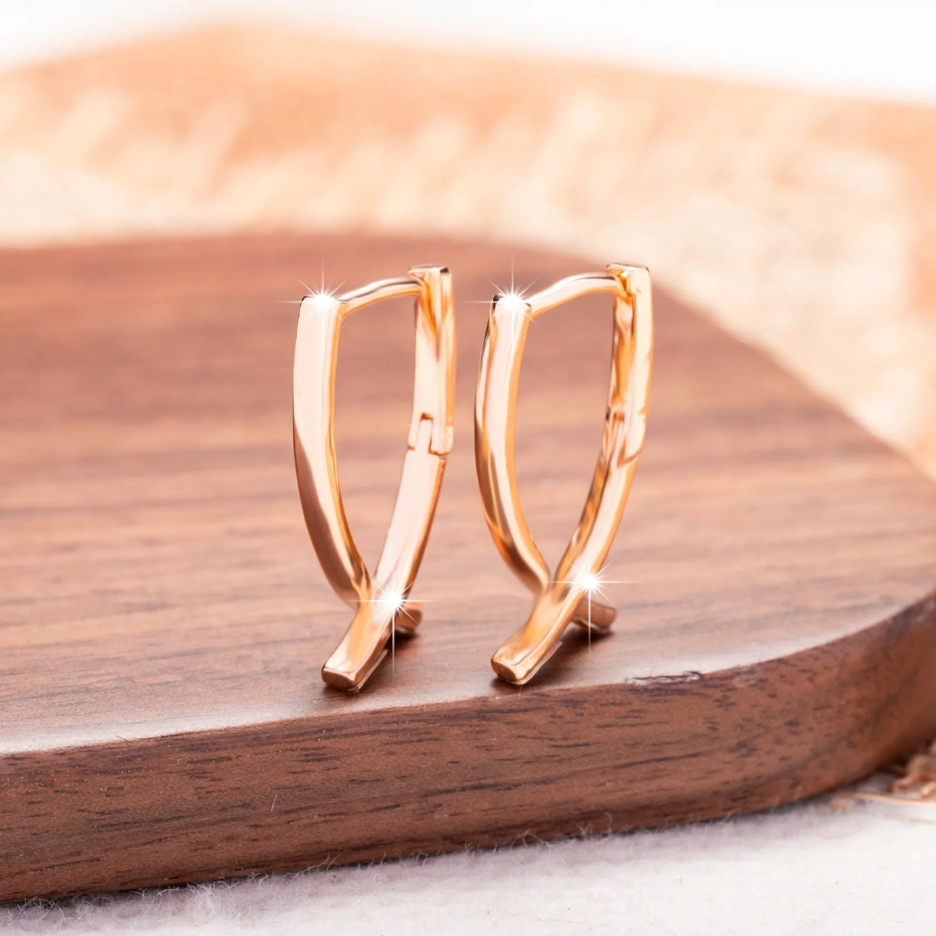 Rose gold cross shaped earrings on a plain background.