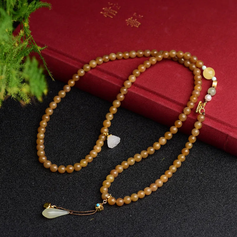 Green jade bracelet with round 6mm beads, beeswax and pine leaf charms on natural background