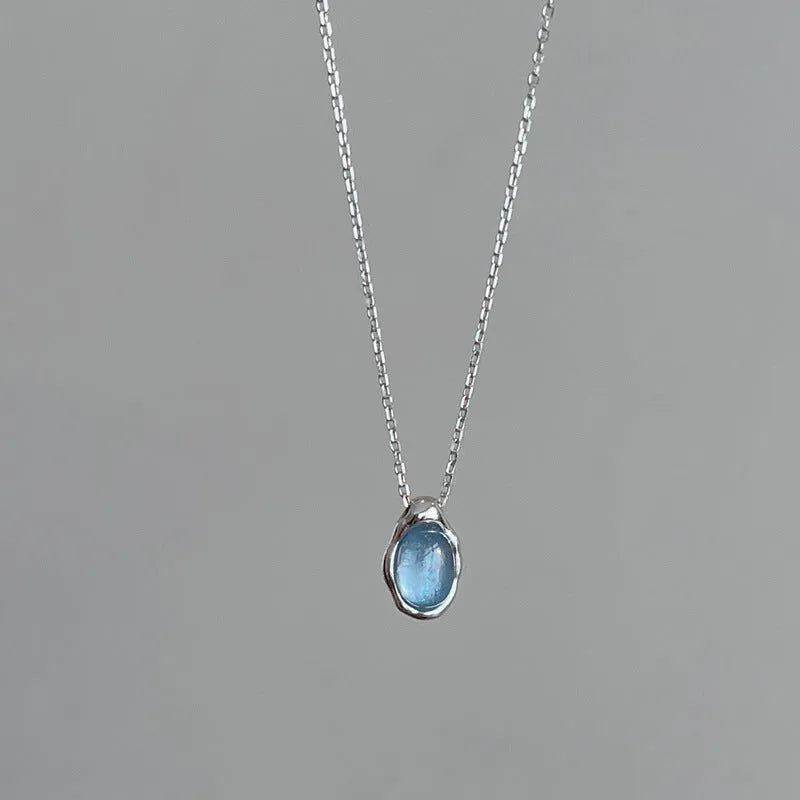 Close-up of a women's navy blue water drop pendant necklace with a platinum-colour electroplated finish on an adjustable cross chain.