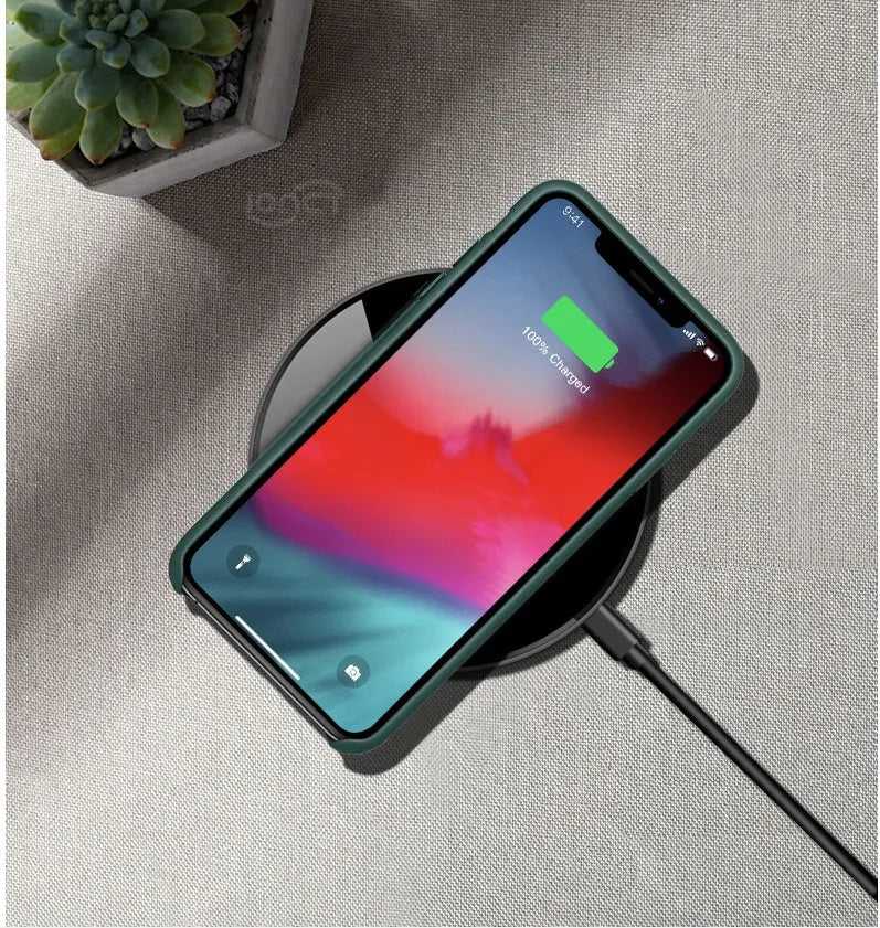 Black QI wireless charging pad on a desk, showing its non-slip silicone base.