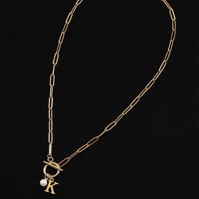 Stainless steel clip chain necklace with raised letter A pendant and imitation pearl in gold colour on a white background