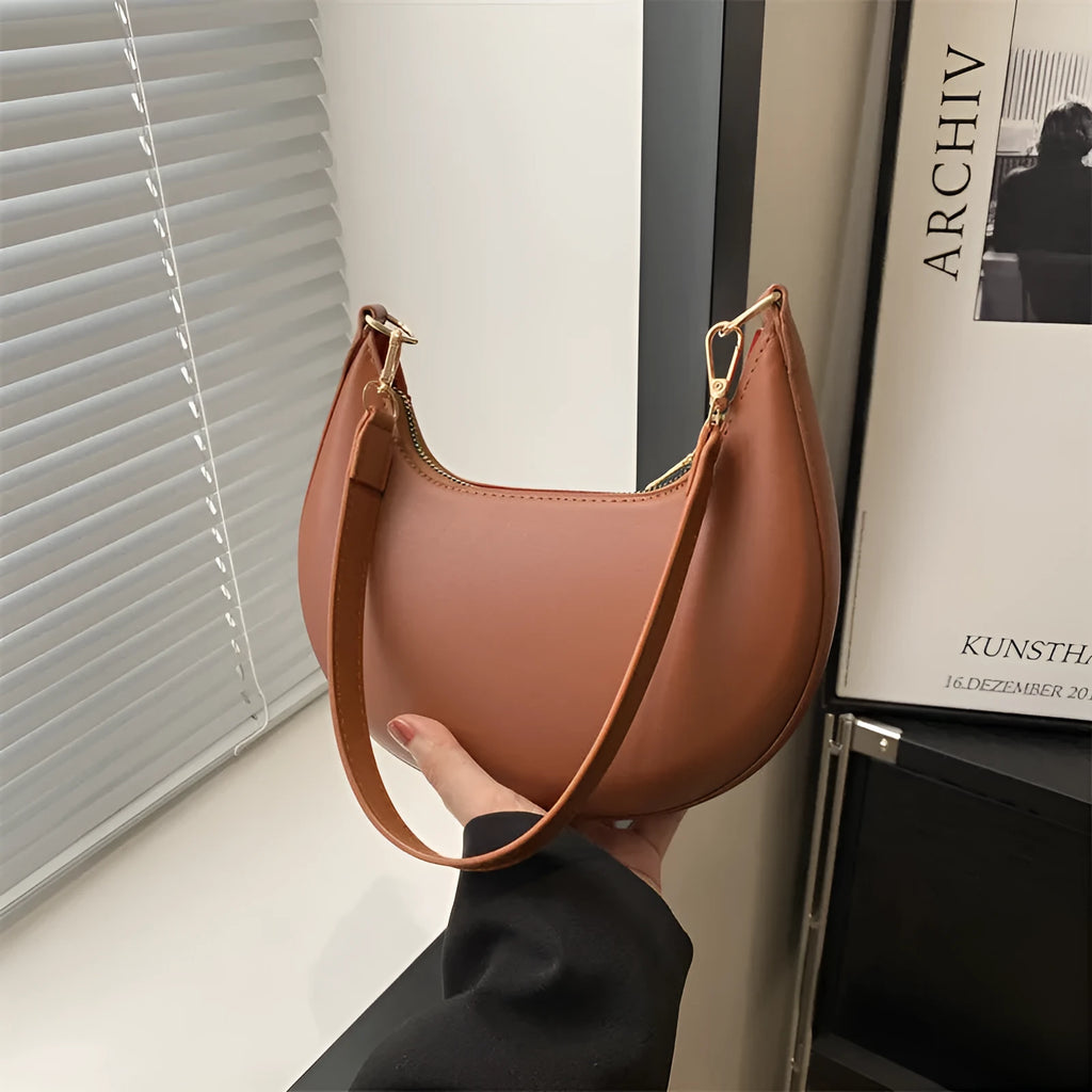Round black women's one-shoulder underarm bag with sewing line details and a single strap.