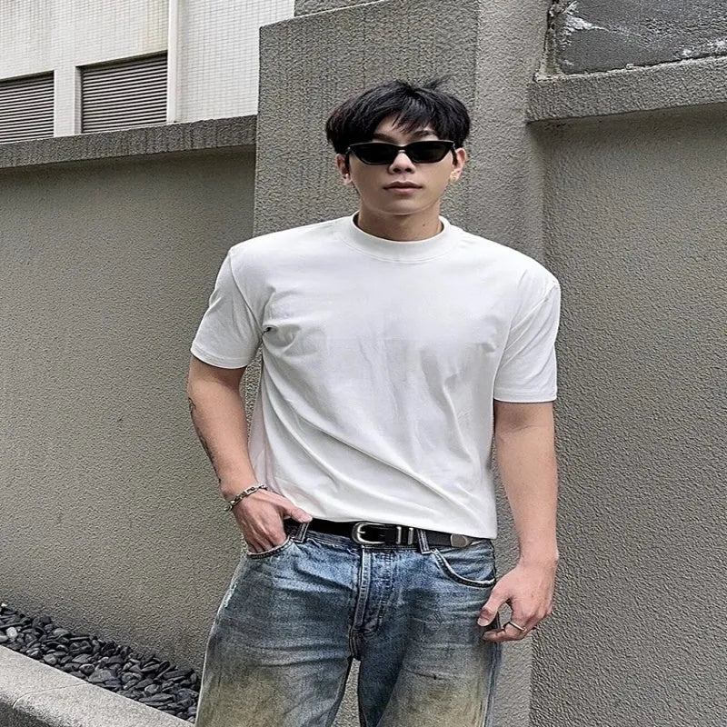 Man wearing a loose-fit grey cotton short-sleeve t-shirt with a half turtleneck cuff shoulder detail.