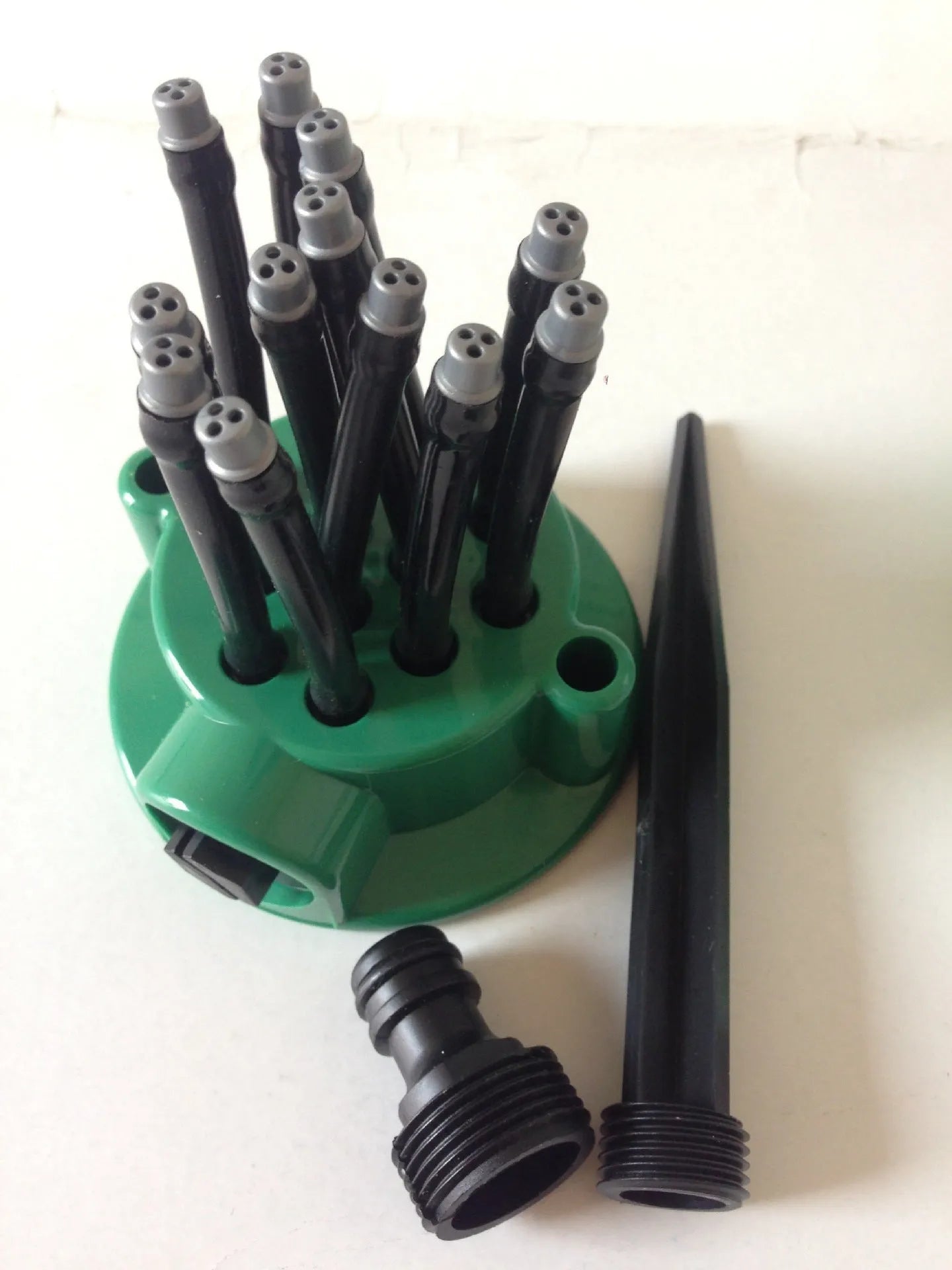 Green adjustable garden sprinkler with bendable spray noodles on 9cm diameter base