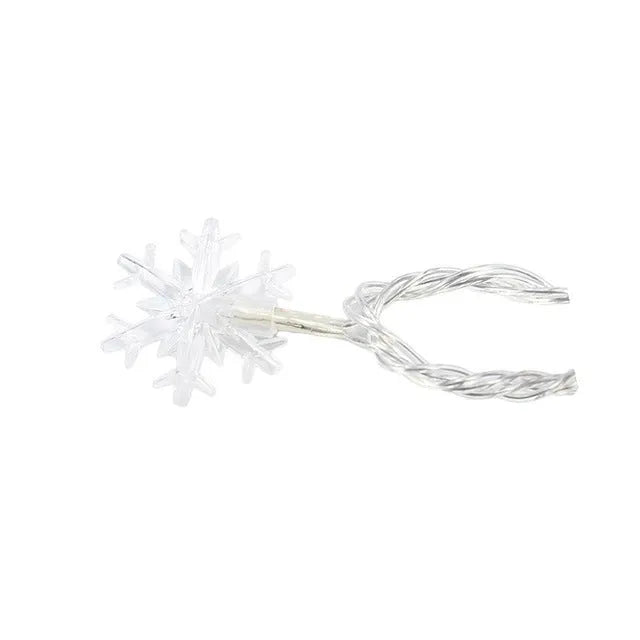 Battery powered LED snowflake string lights in warm white on a garden tree branch for Christmas decoration