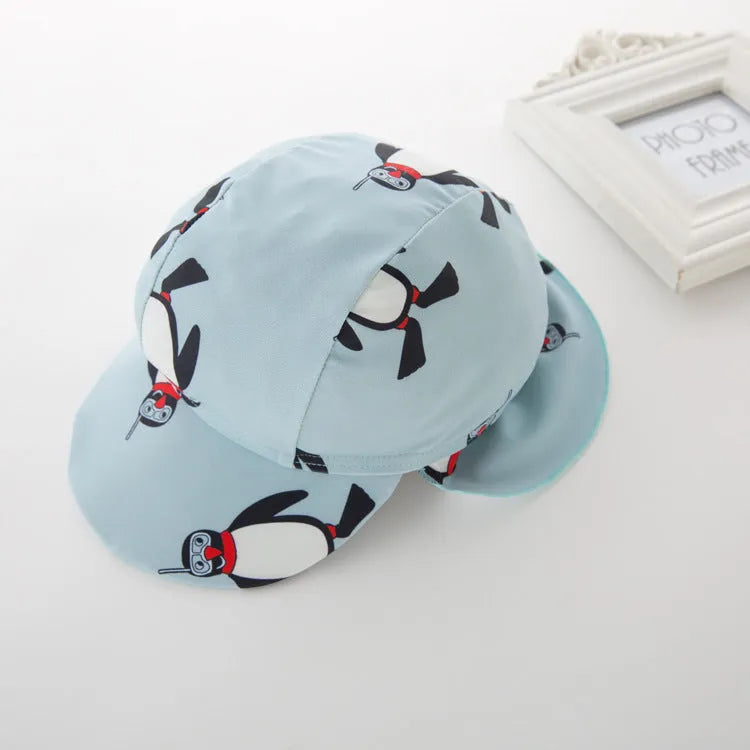 Toddler boy wearing a penguin print long sleeve one-piece swimsuit and matching swimming cap.