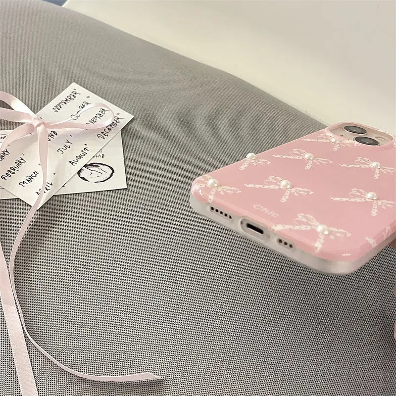 Pink soft TPU iPhone case with three-dimensional pearl dot bow, compatible with iPhone 11 to 15 Pro Max.